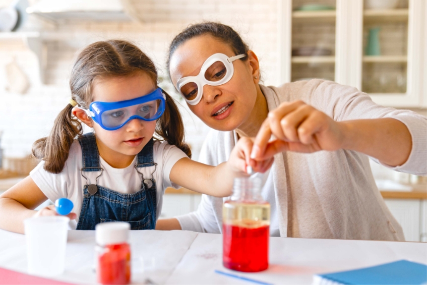 mother and daughter working on a science project with goggles and a beaker